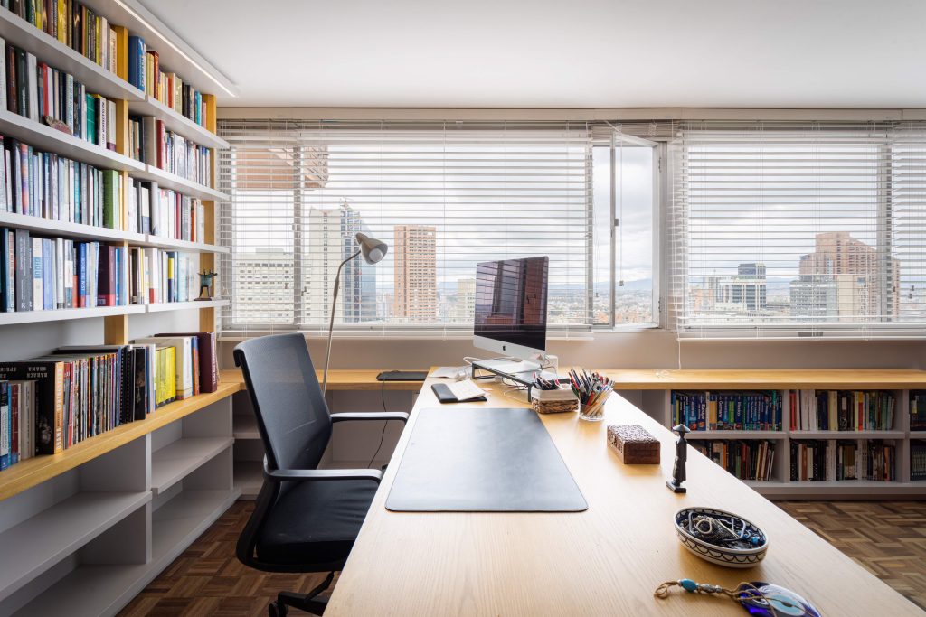 Bright modern office with bookshelves and cityscape view in Bogotá.